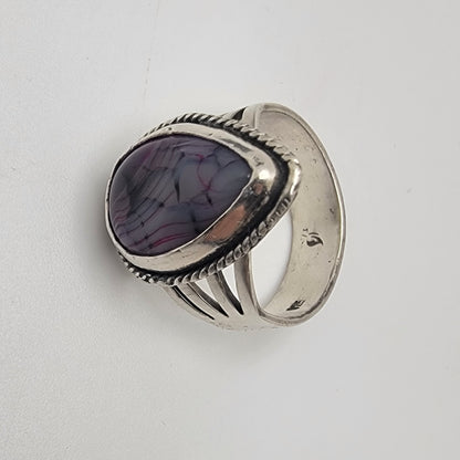 Silver ring with a purple stone on a light gray background