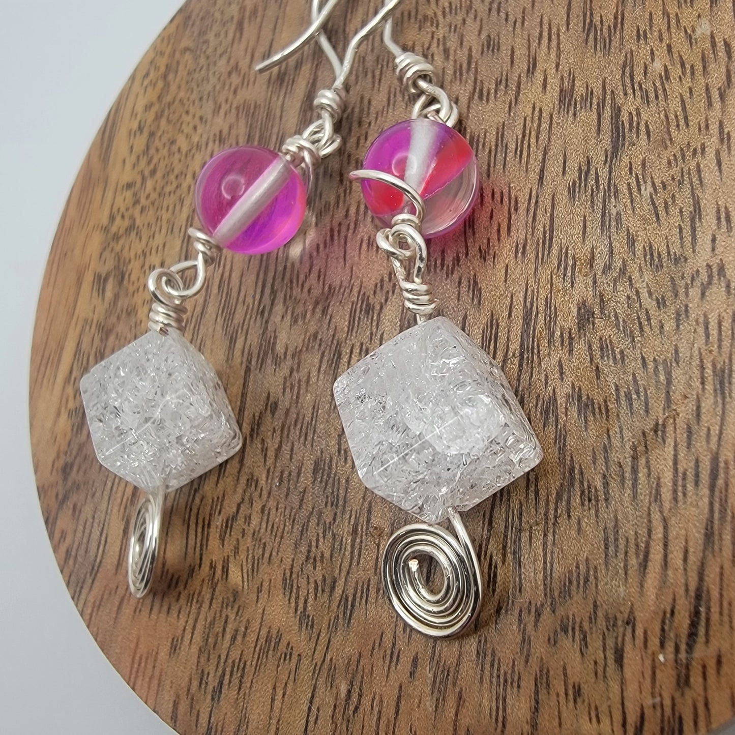 Earrings with pink beads and clear crystal-like stones on a wooden surface