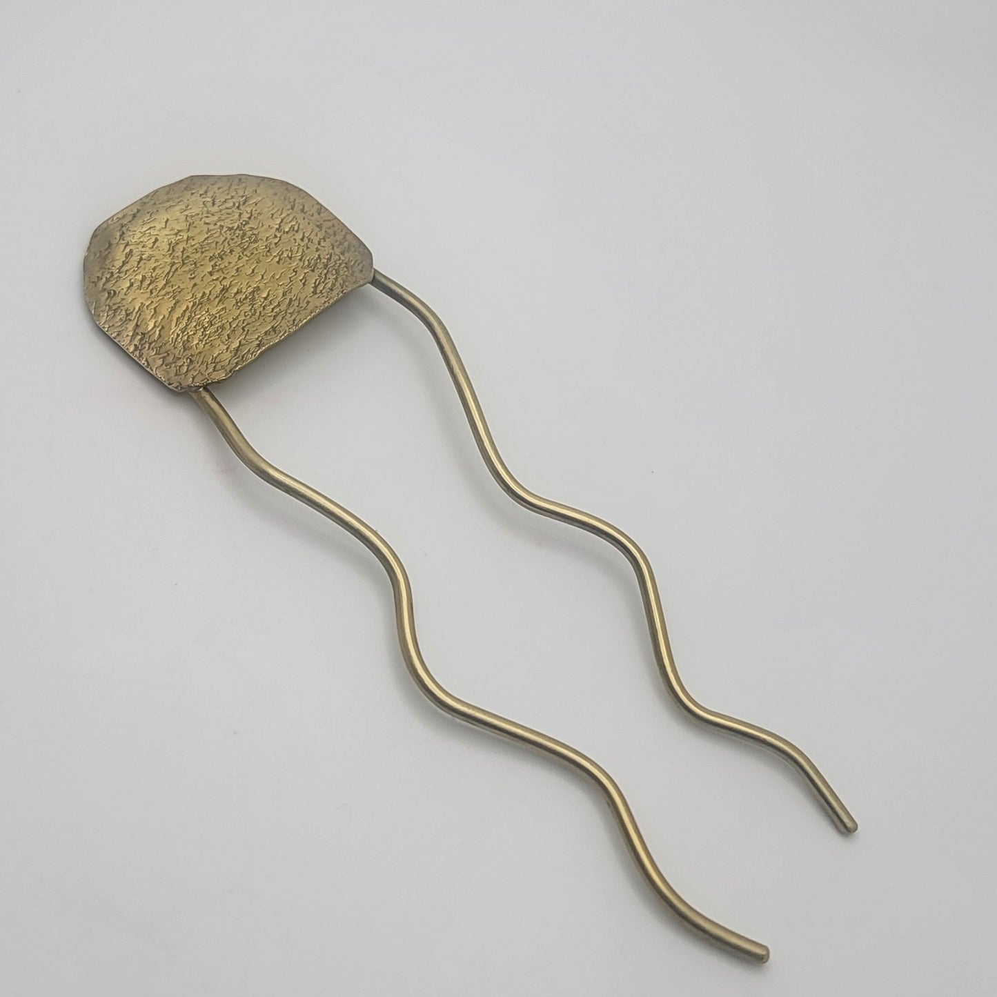 Bronze-colored hairpin on a light gray background