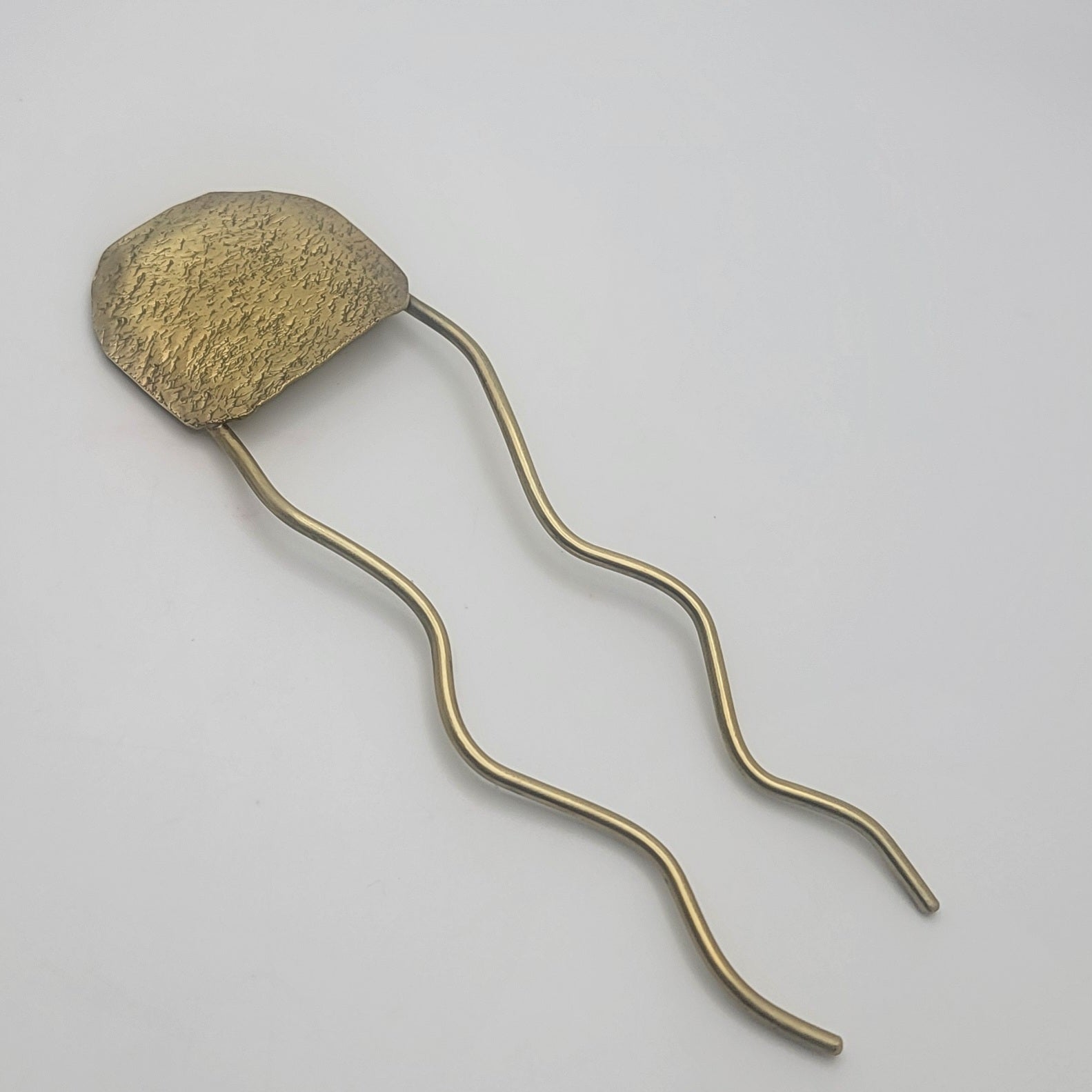 Bronze-colored hairpin on a light gray background