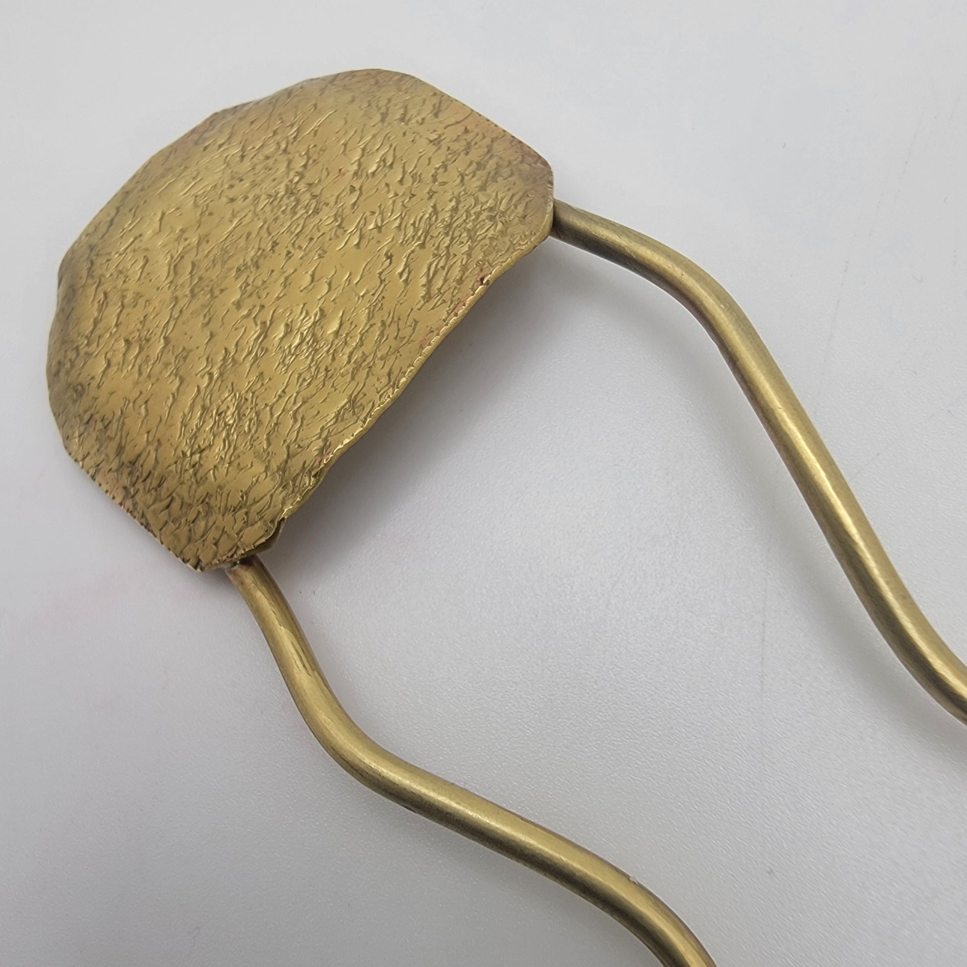 Gold-colored hair clip on a light gray background