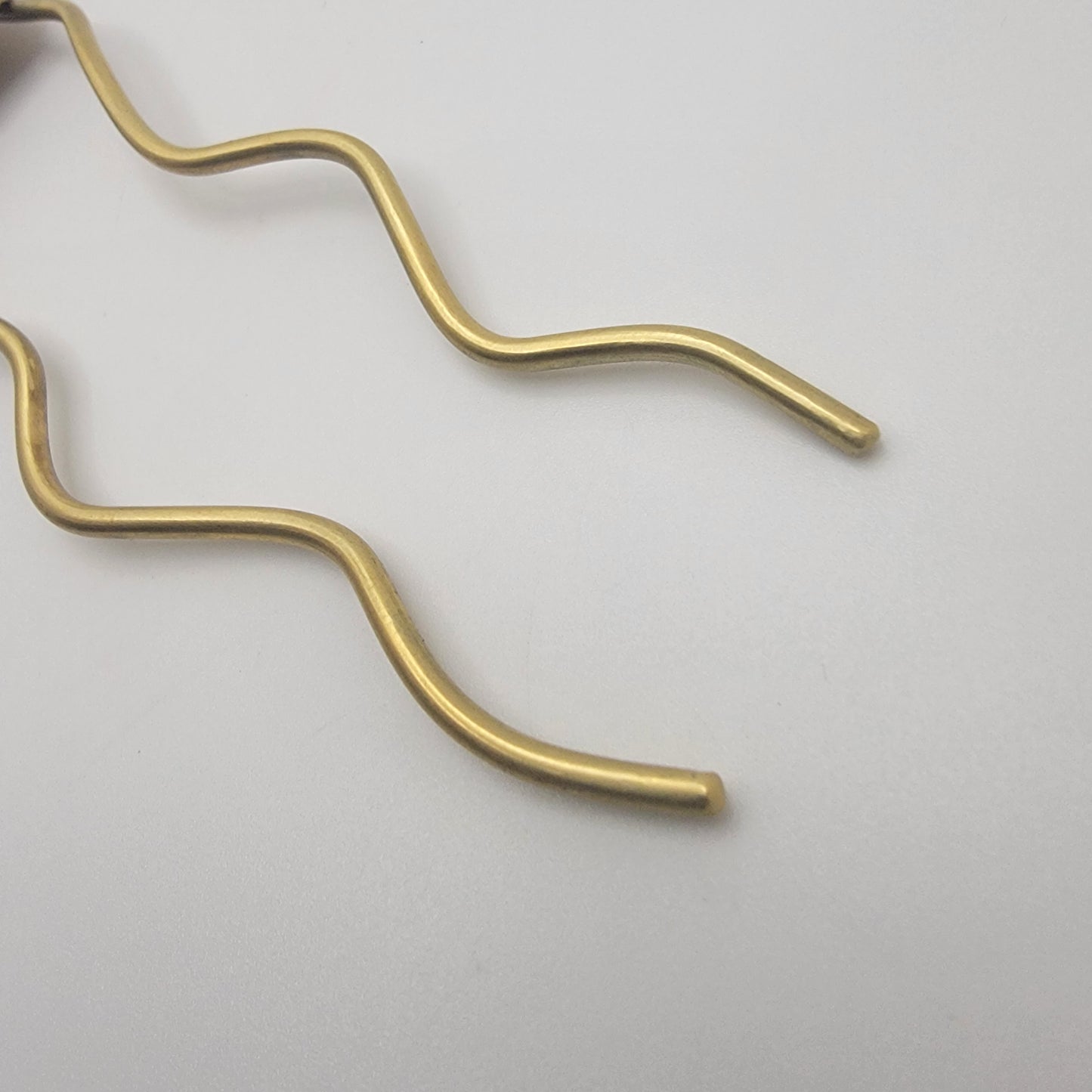 Ends of brass hair pins on white background