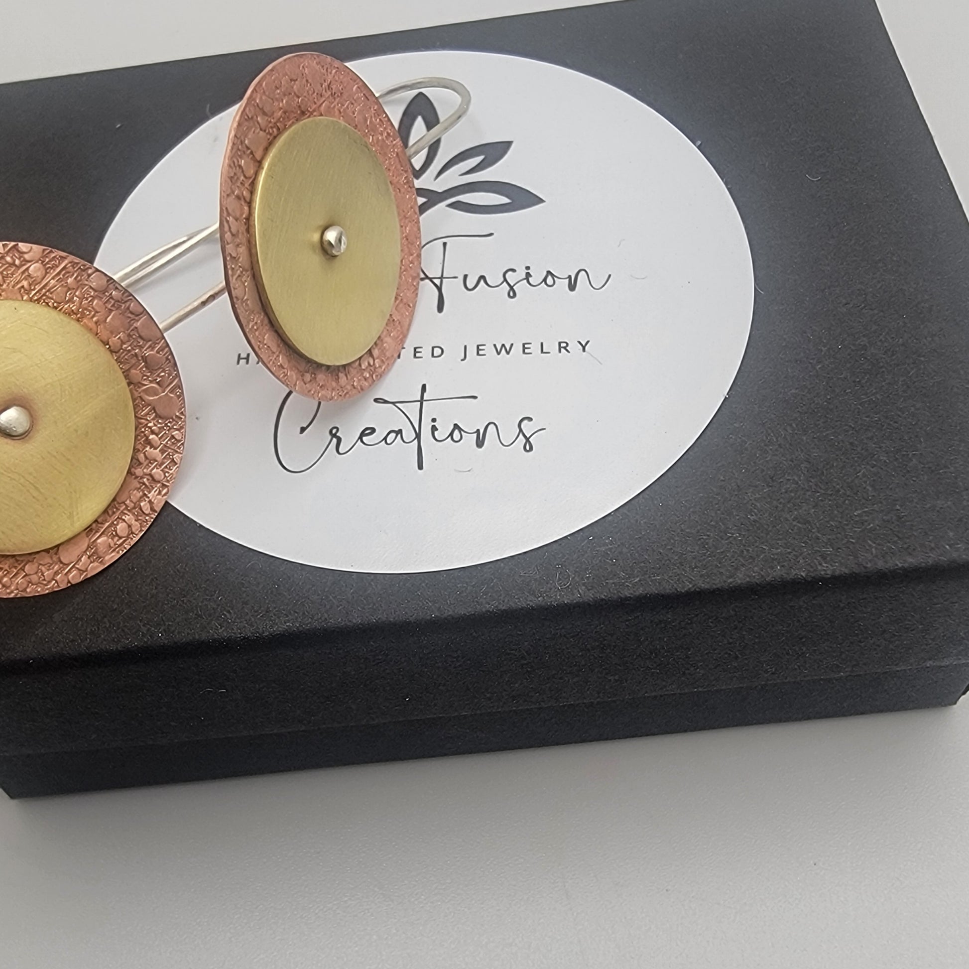 Jewelry earrings on a Fusion Creations branded card with a black box background