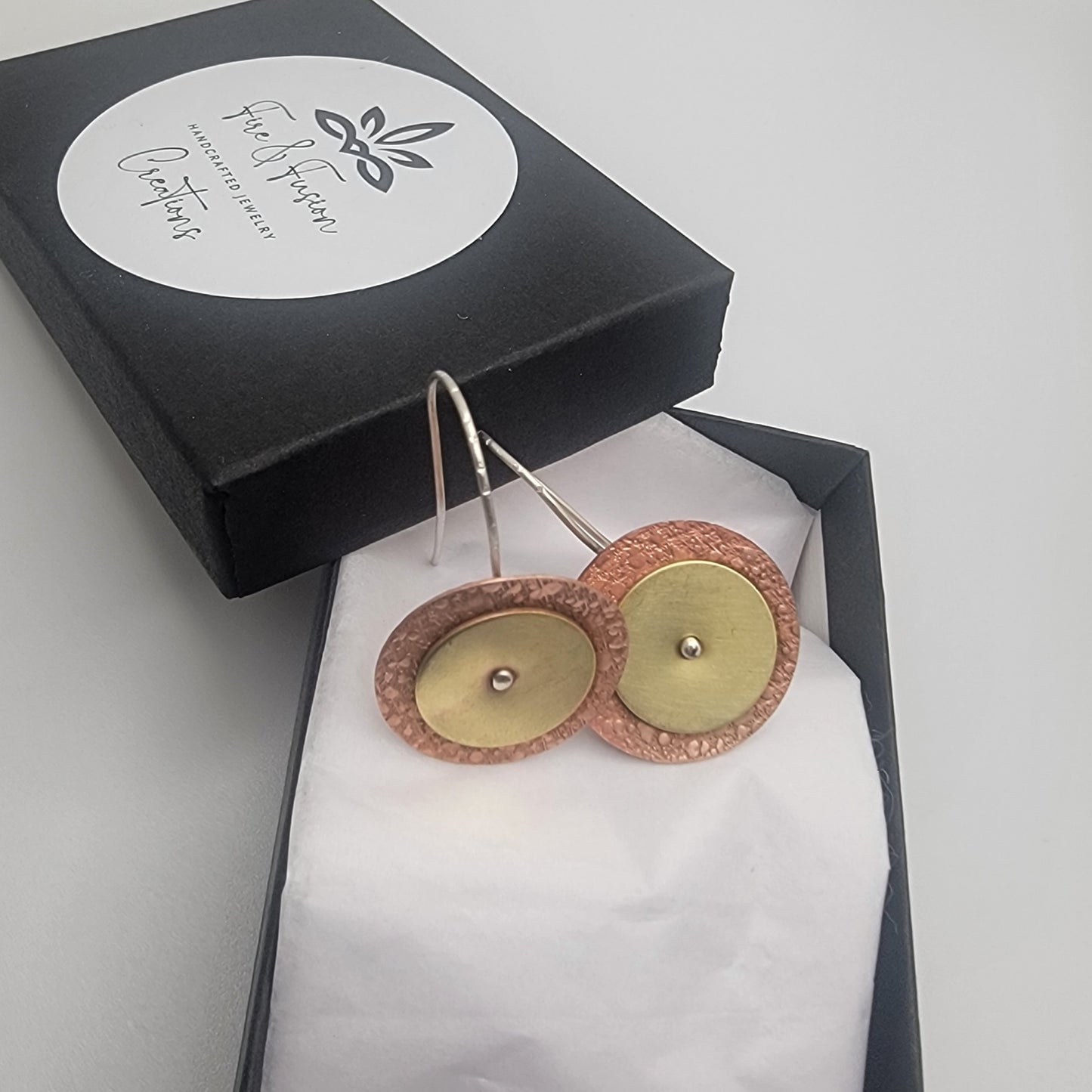 Gold and rose gold earrings in a black box with a brand label.