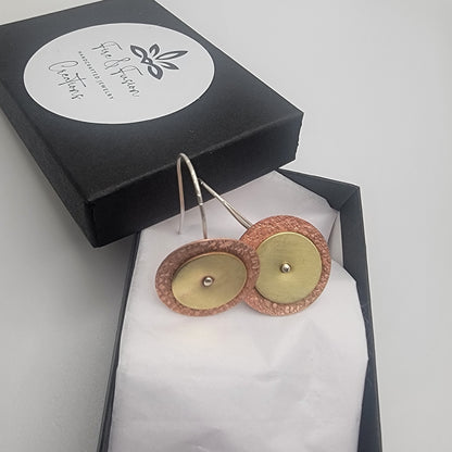 Gold and rose gold earrings in a black box with a brand label.