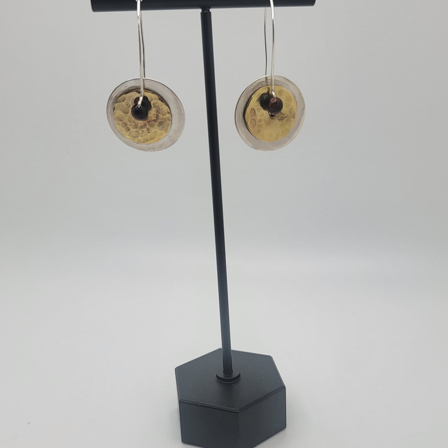 Pair of earrings on a black stand against a white background