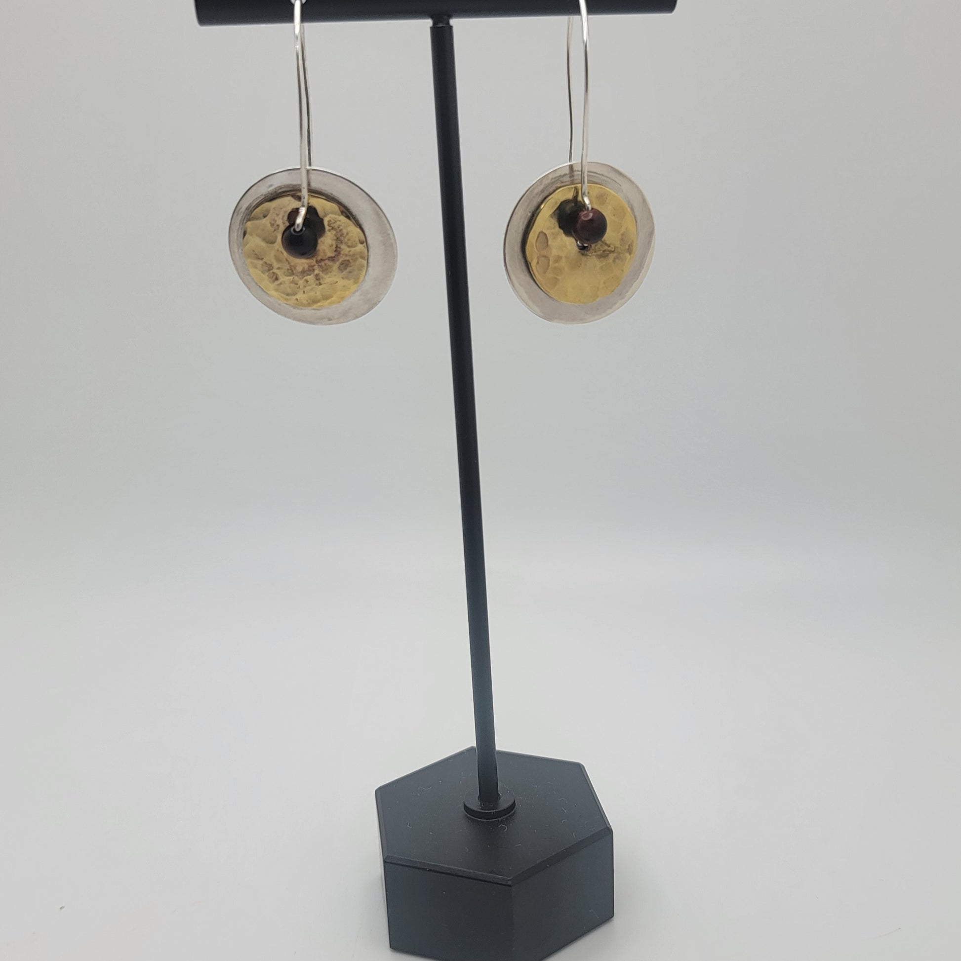 Pair of earrings on a black stand against a white background