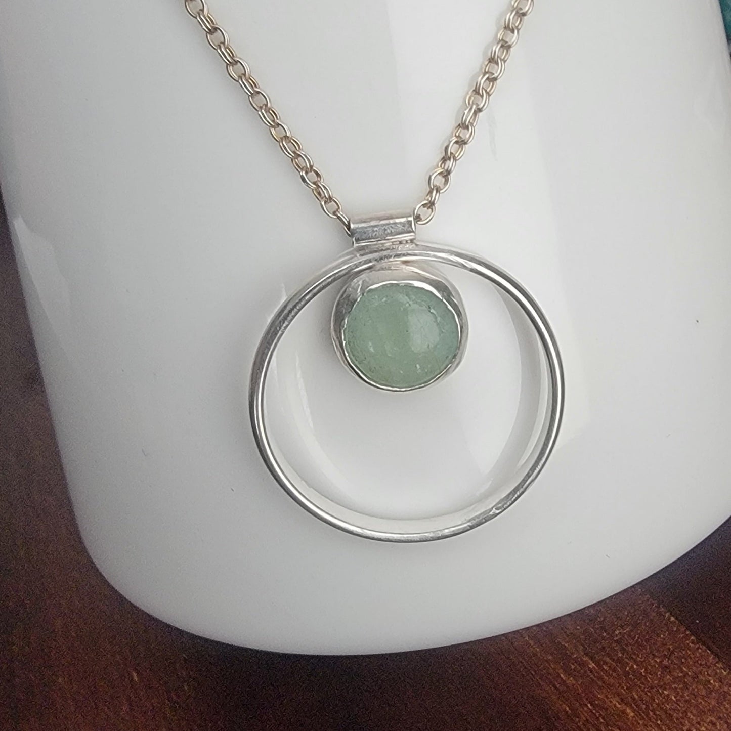 Necklace with a green pendant on a white coffee cup