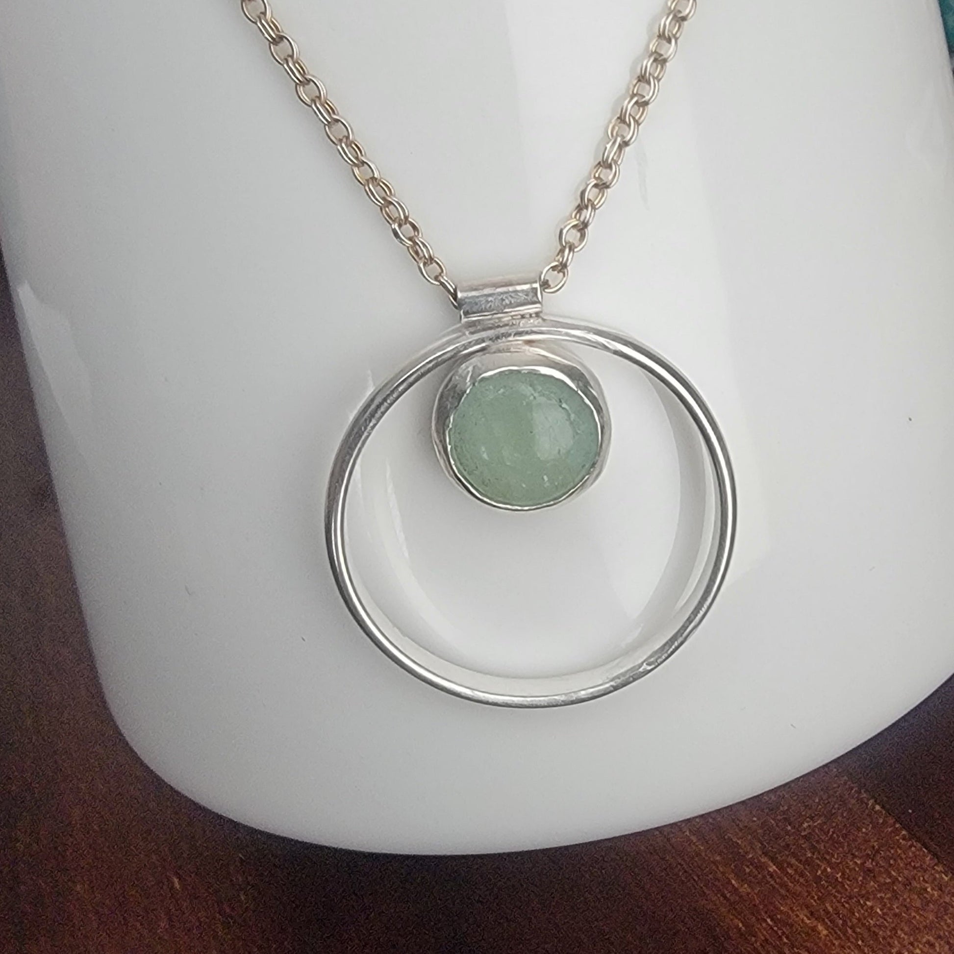 Necklace with a green pendant on a white coffee cup