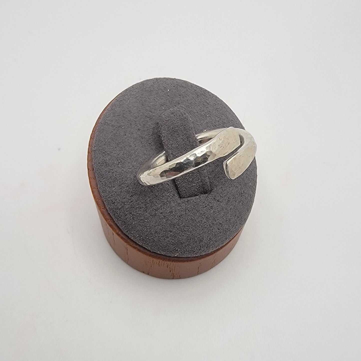 Silver ring on a wooden and gray foam ring holder against a white background