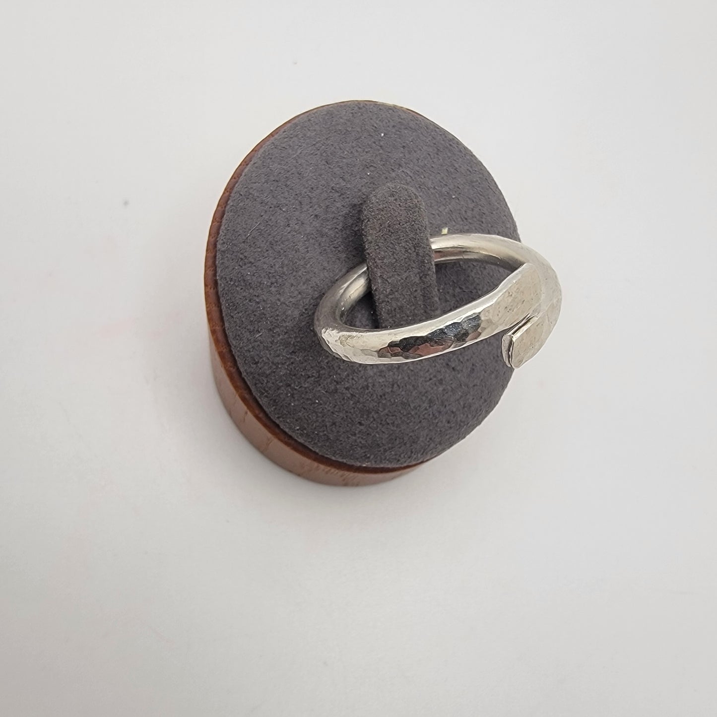 Silver ring on a gray cushion with a white background