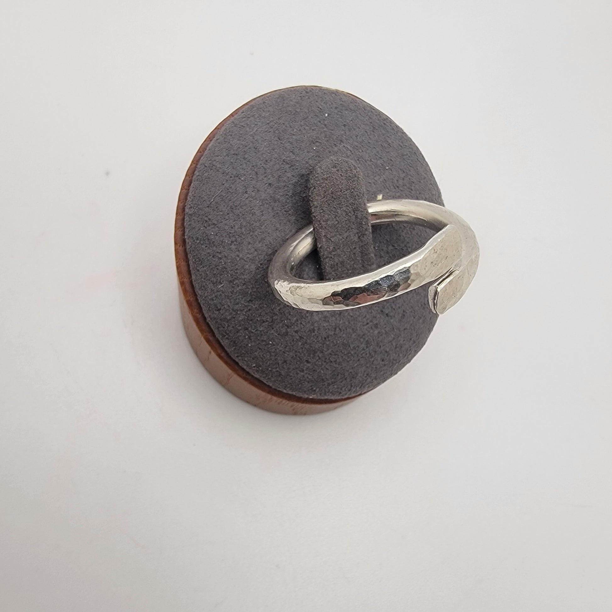 Silver ring on a gray cushion with a white background