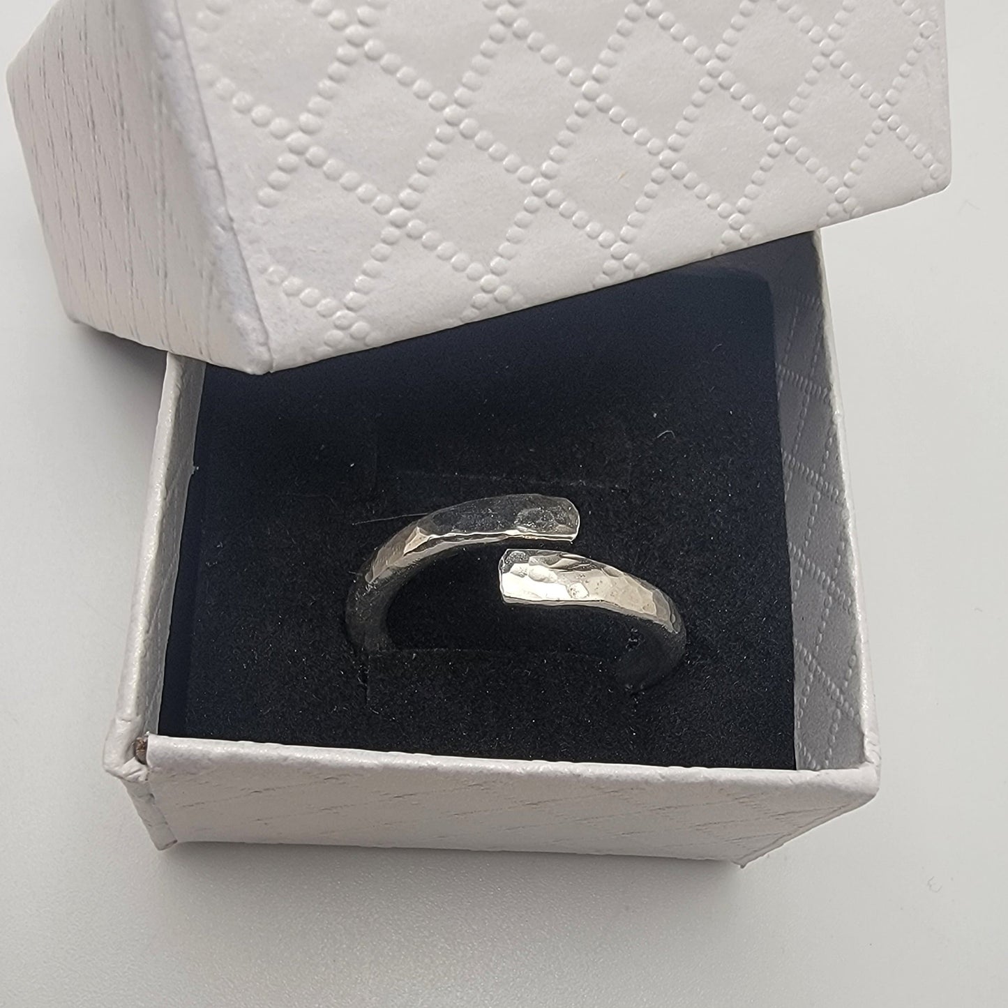 Silver ring in an open white box on a light gray background
