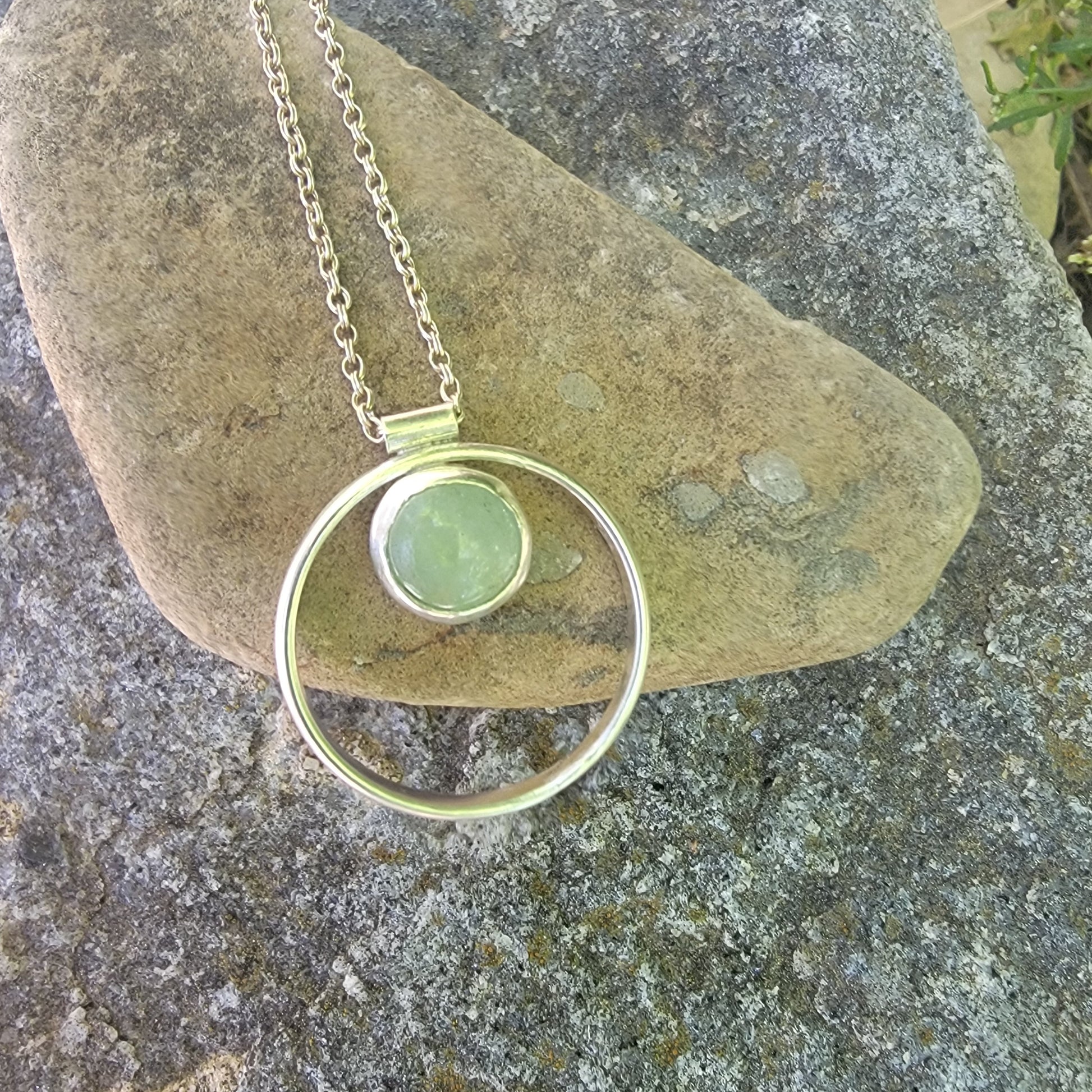 Necklace with a green pendant on a stone surface