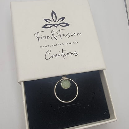 Silver ring with green stone in a 'Fire & Fusion Handcrafted Jewelry Creations' box.