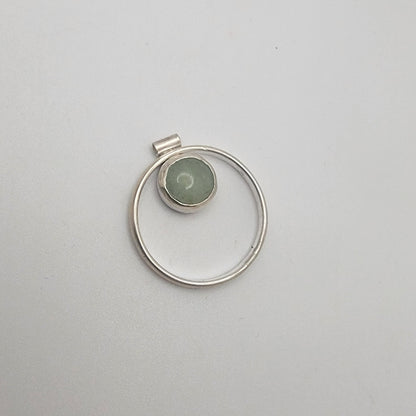 Silver pendant with a green stone on a light gray background