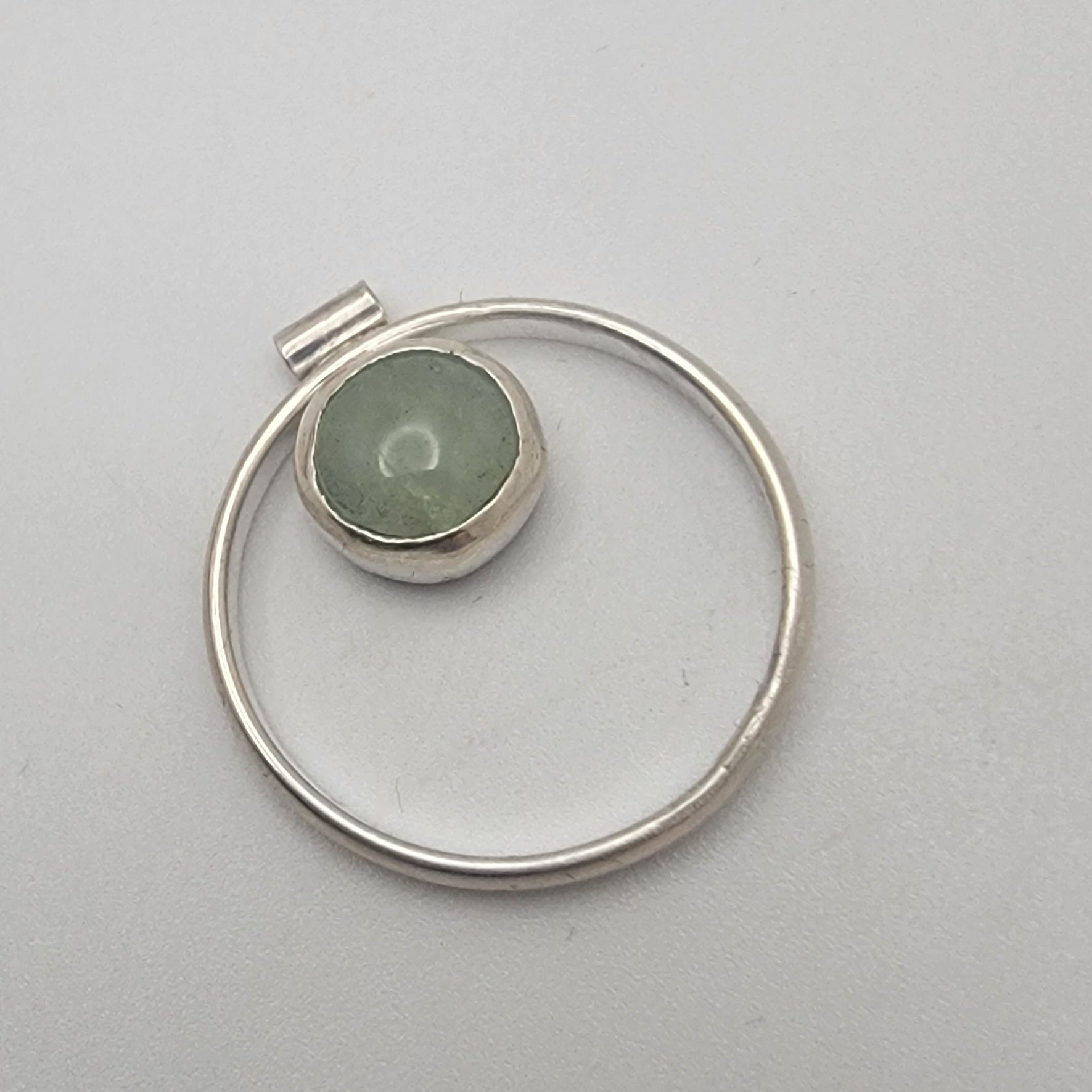 Silver pendant with a green stone on a light gray background