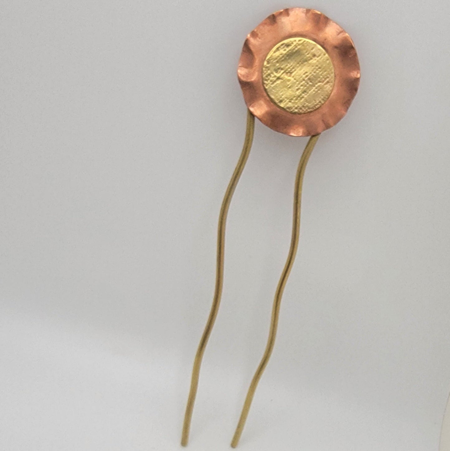 Gold and copper hairpin on a light gray background