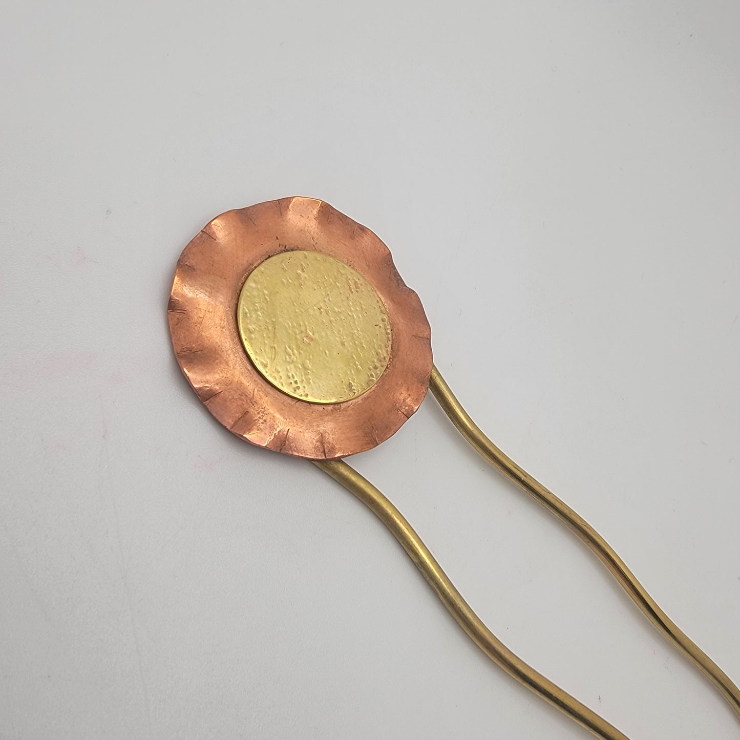 Copper and gold hairpin on a light gray background