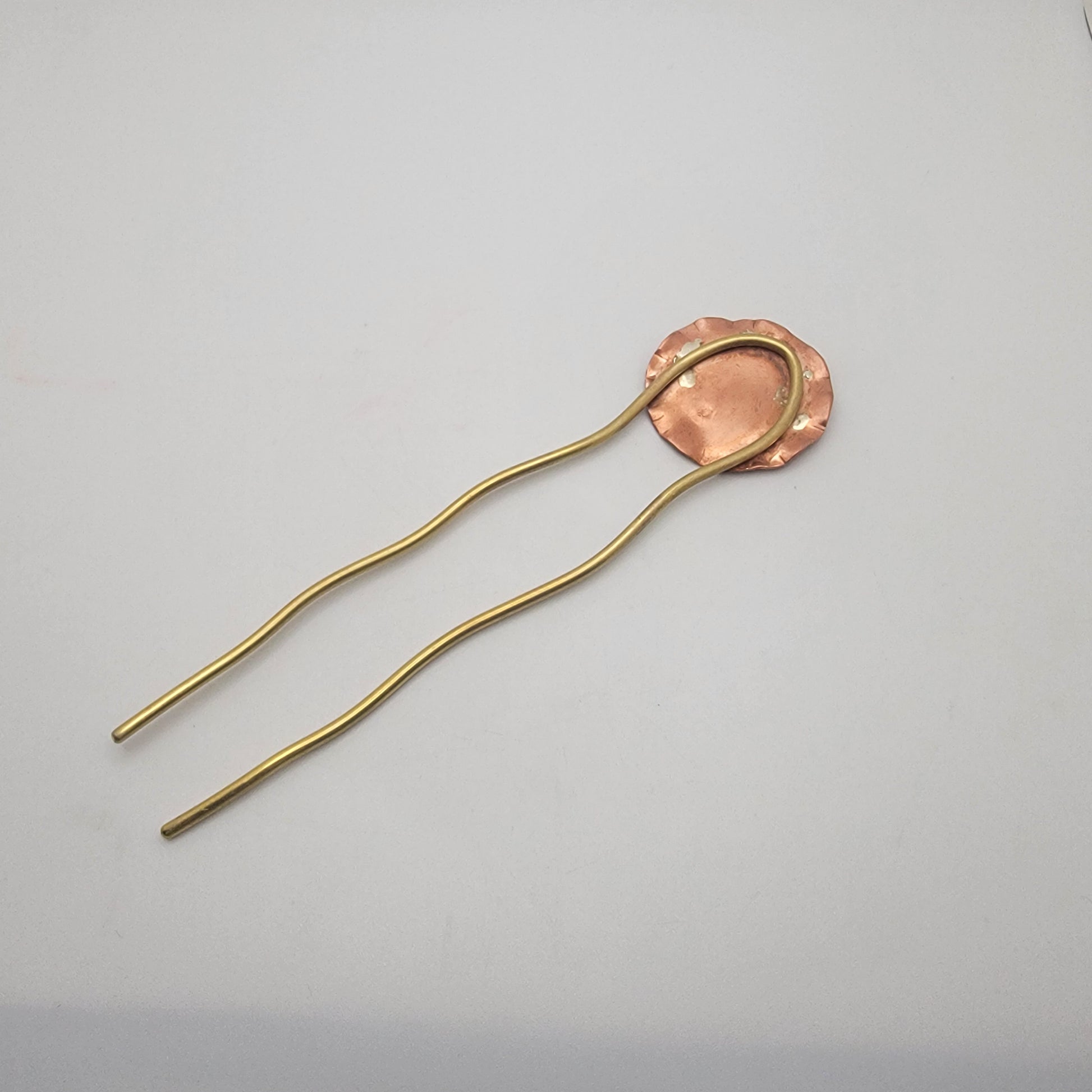 Gold hairpin with a copper disc on a gray background