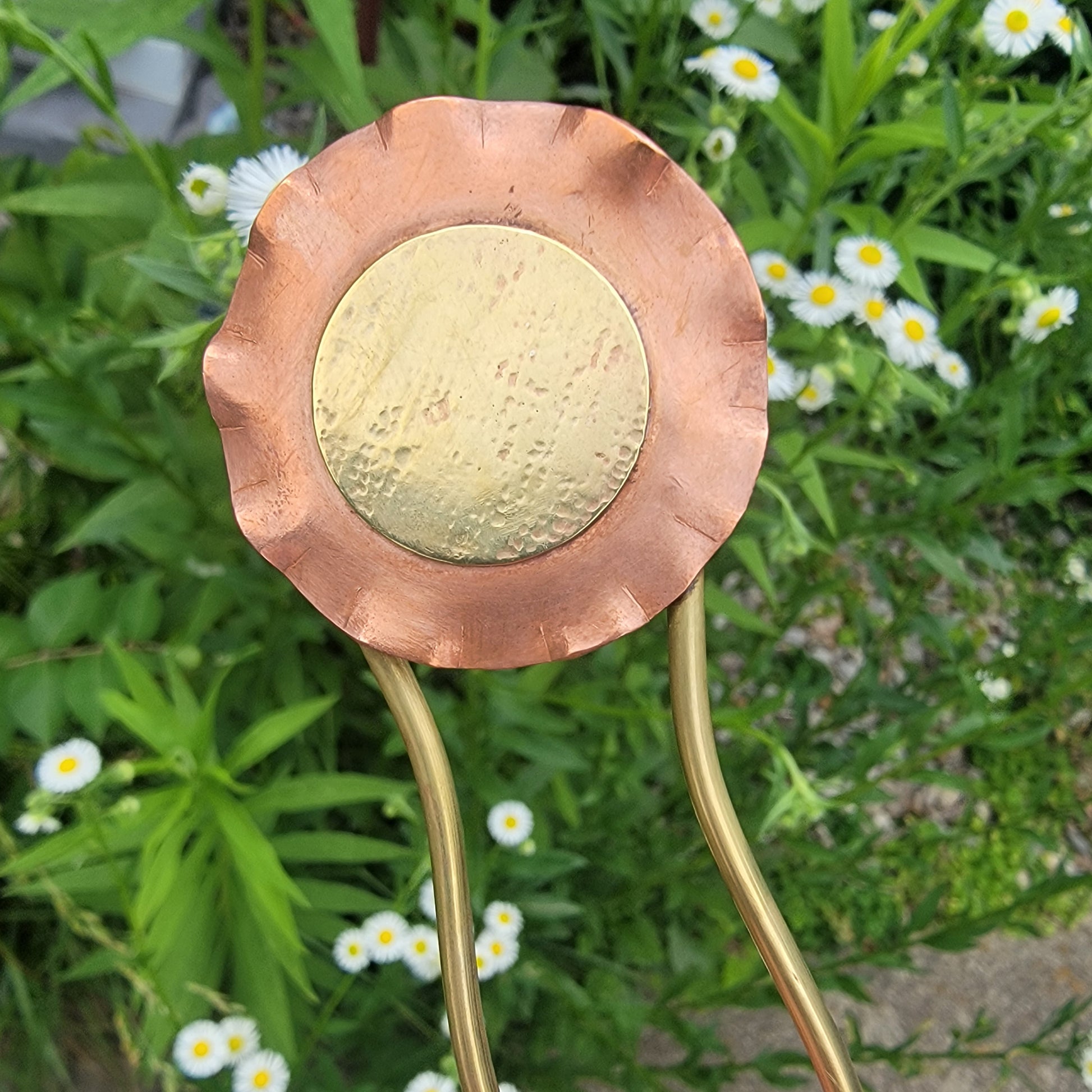 Copper and brass hairpin with greenery and white flowers in the background