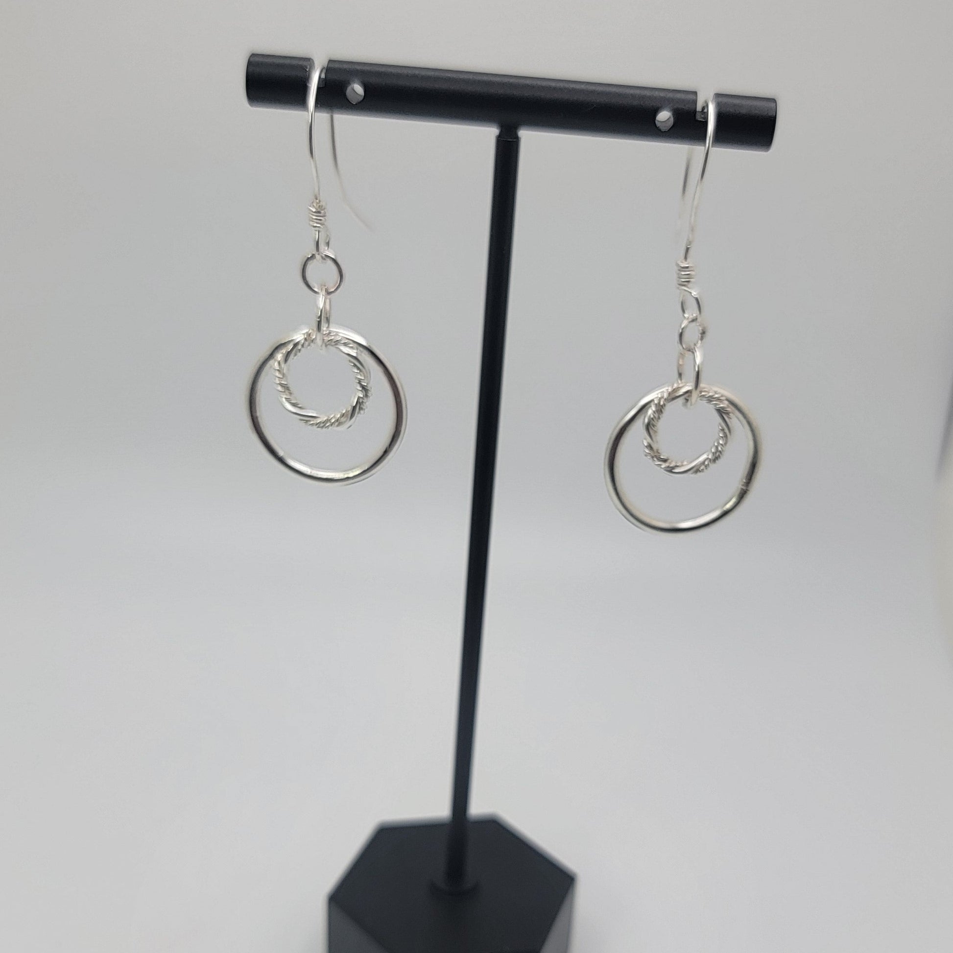 Black jewelry display with silver earrings on a white background