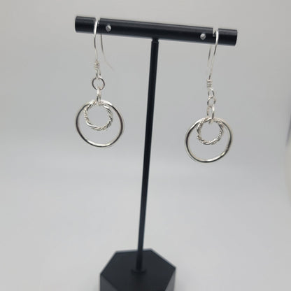 Black jewelry display with silver earrings on a white background