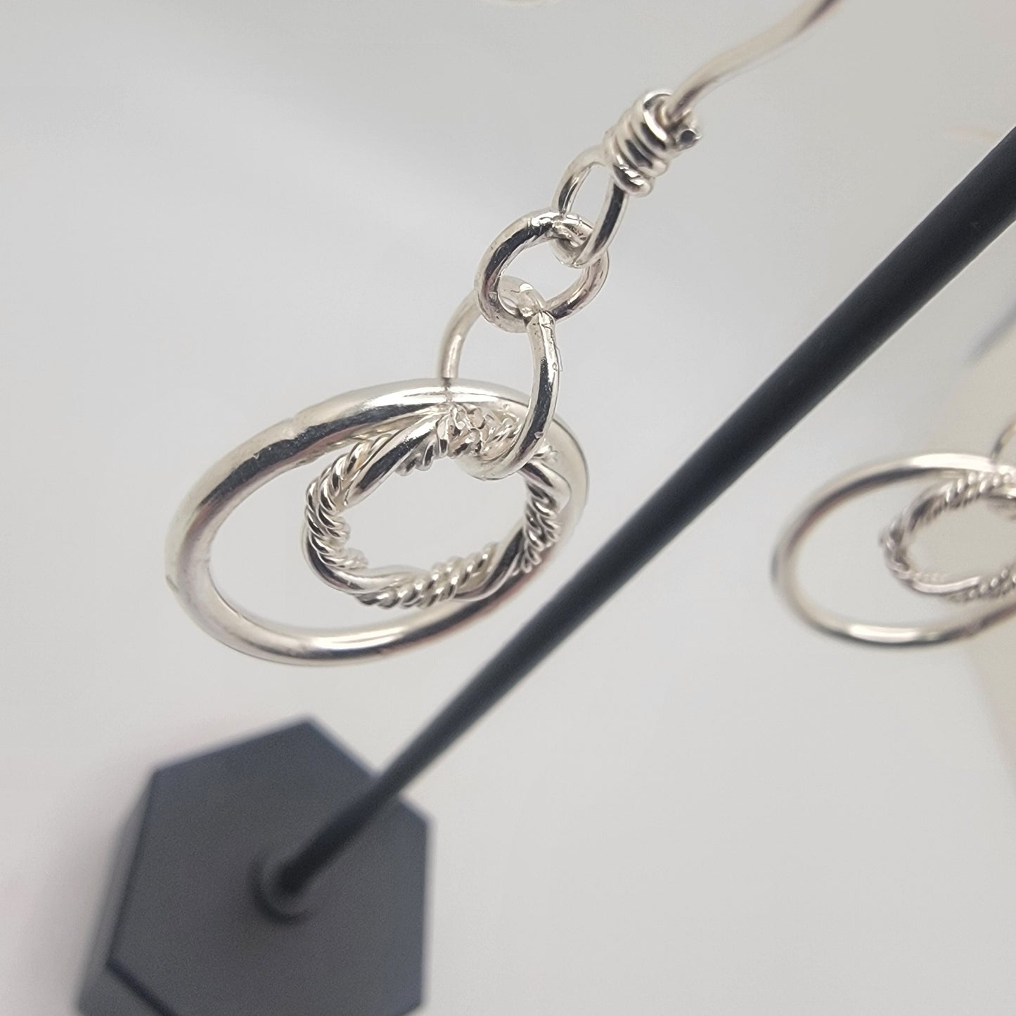 Silver hoop earrings on a stand with a white background