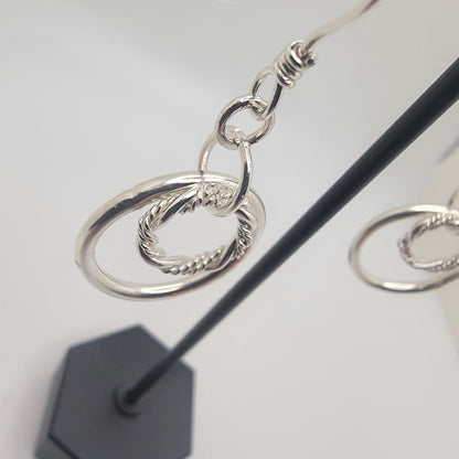Silver hoop earrings on a stand with a white background