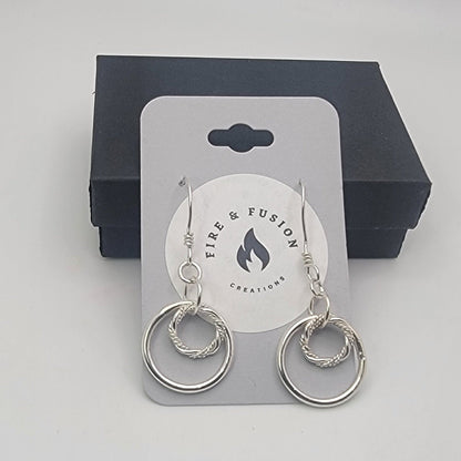 Silver hoop earrings on a Fire & Fusion Creations card with a black box in the background.