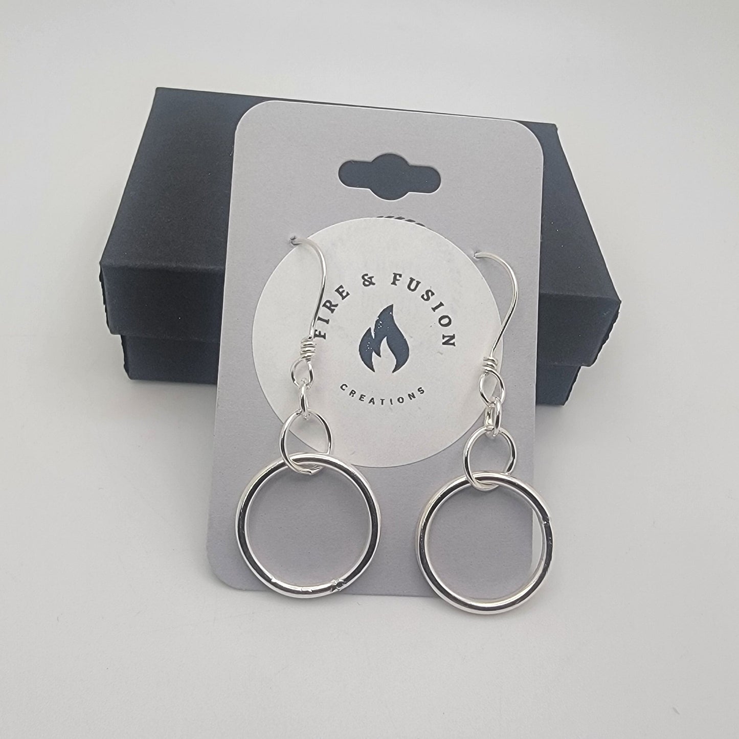 Silver earrings on a logo jewelry card on a gray background