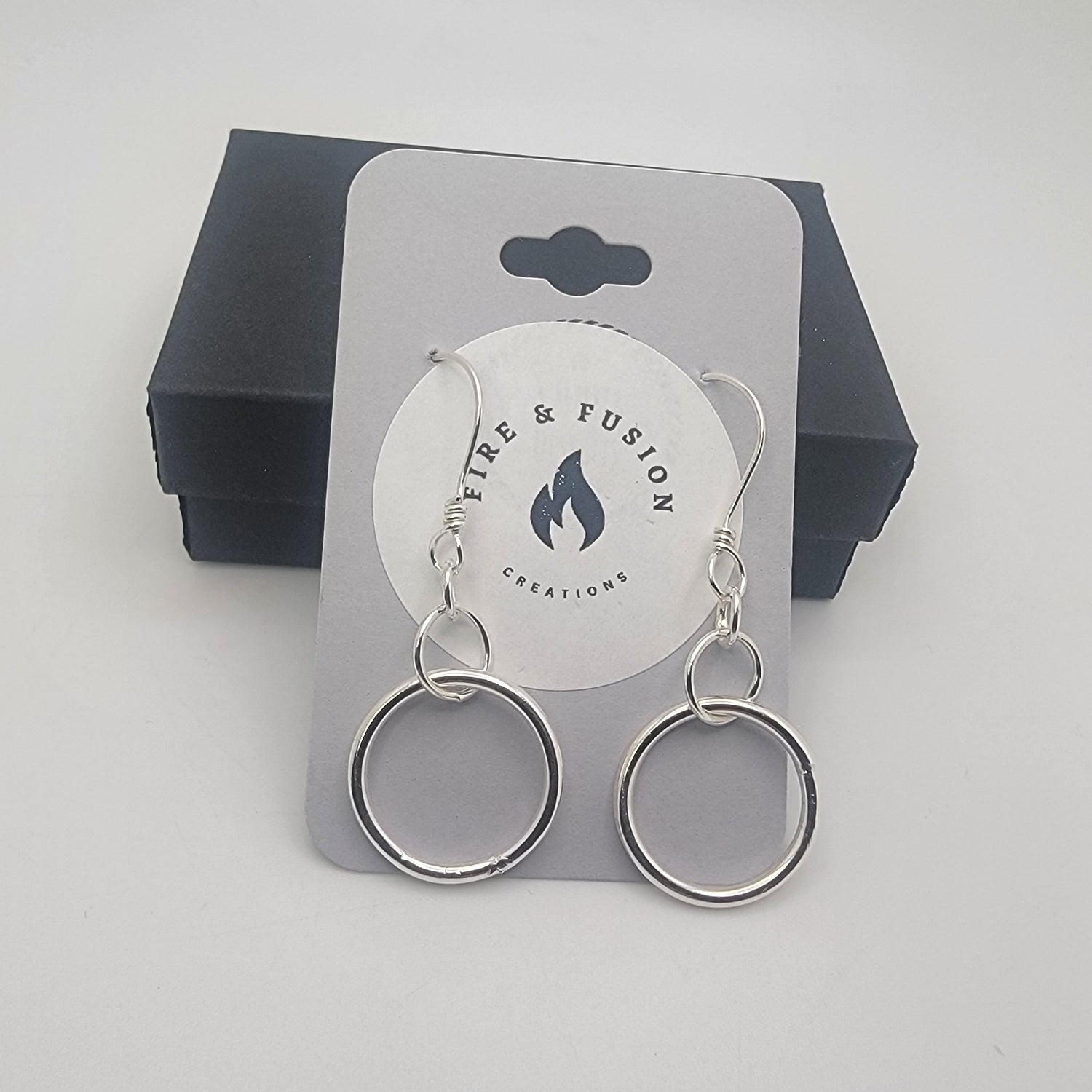 Silver earrings on a logo jewelry card on a gray background