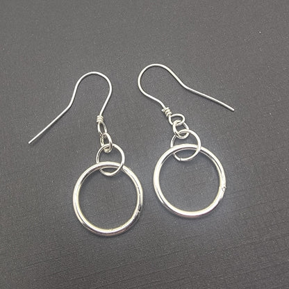 Silver hoop earrings on a dark gray surface