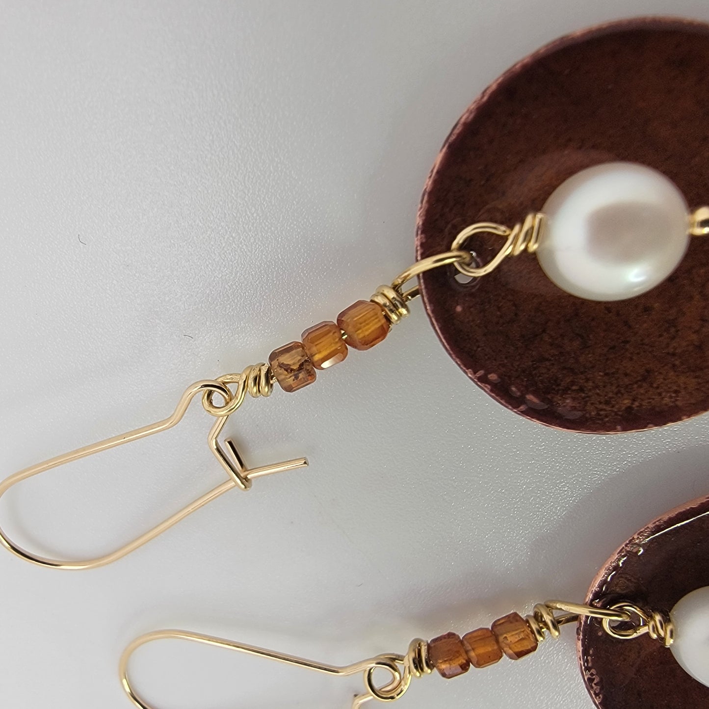 Copper earrings with pearls and brown beads on a white background