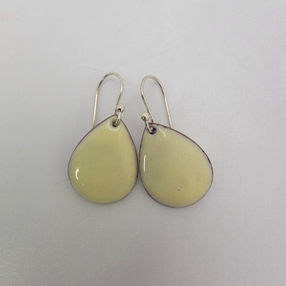 Pair of light yellow teardrop-shaped earrings on a white background