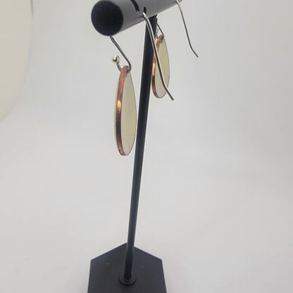 A pair of yellow earrings on a black earring stand on a white background