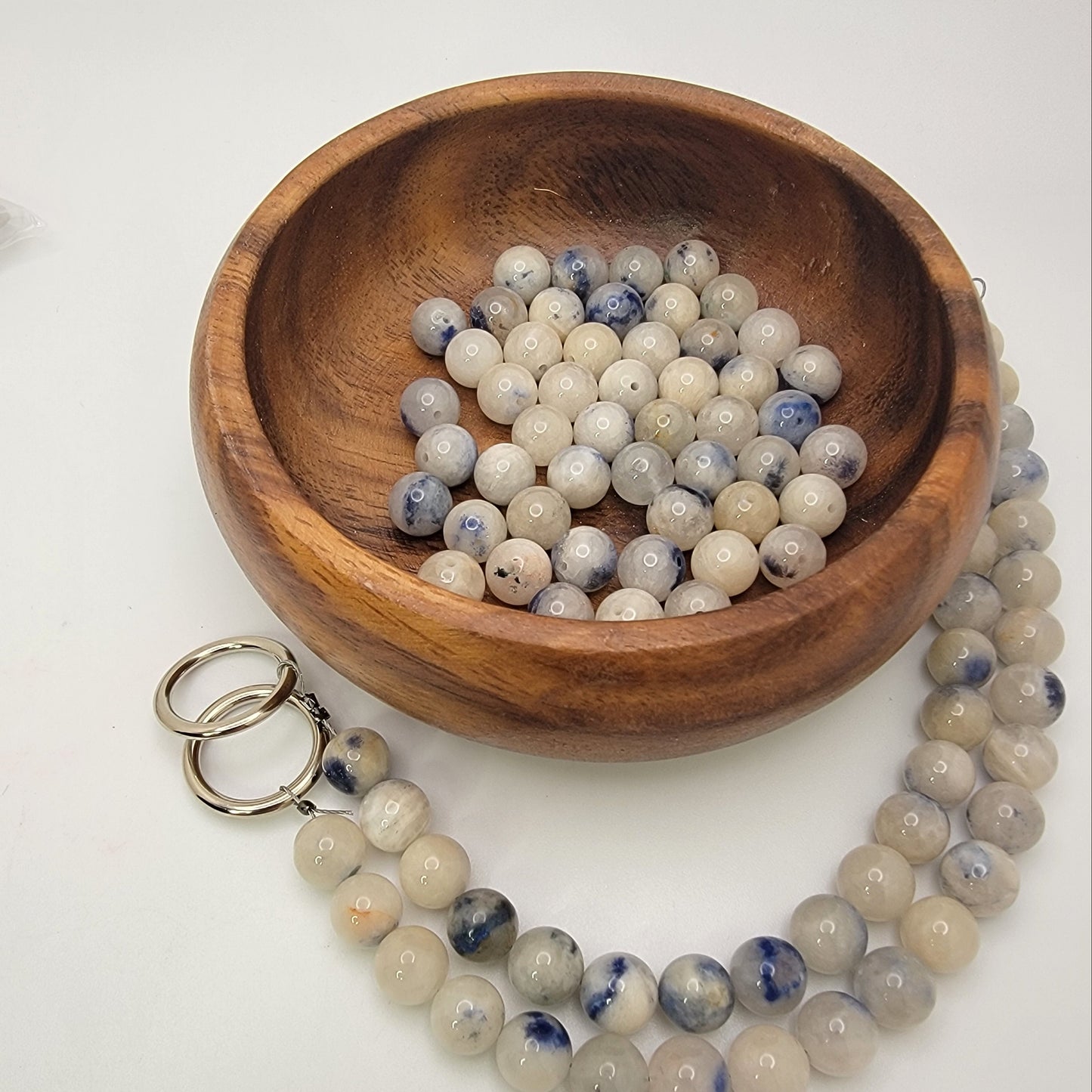 Wooden bowl with blue and white beads on a white background