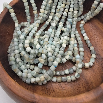 Small square blue beads in wood dish
