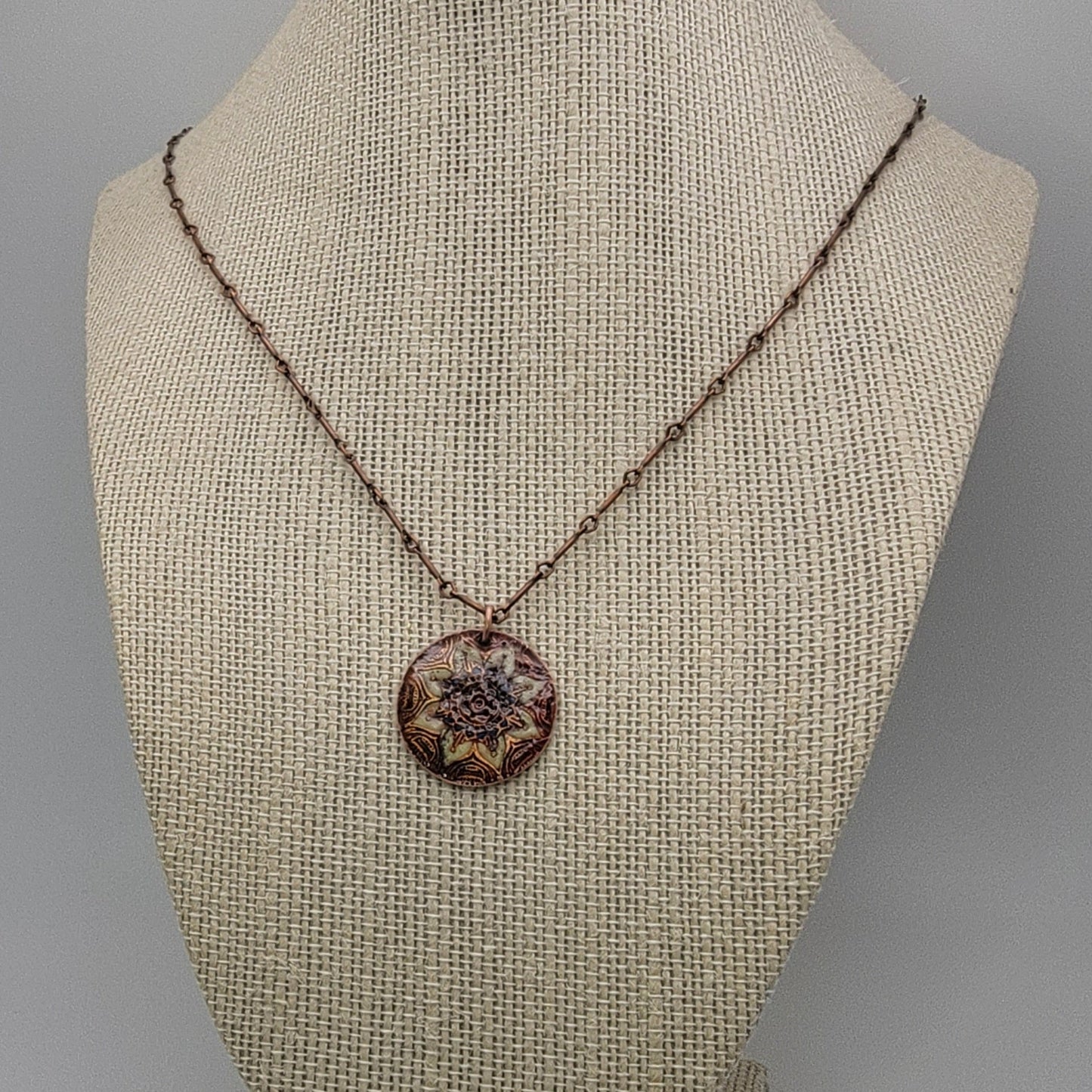 Necklace with a decorative mandala pendant on a mannequin bust against a neutral background