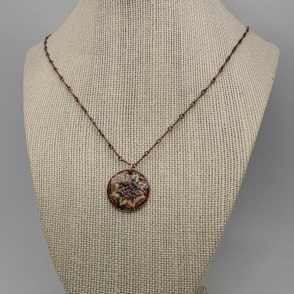 Necklace with a decorative mandala pendant on a mannequin bust against a neutral background
