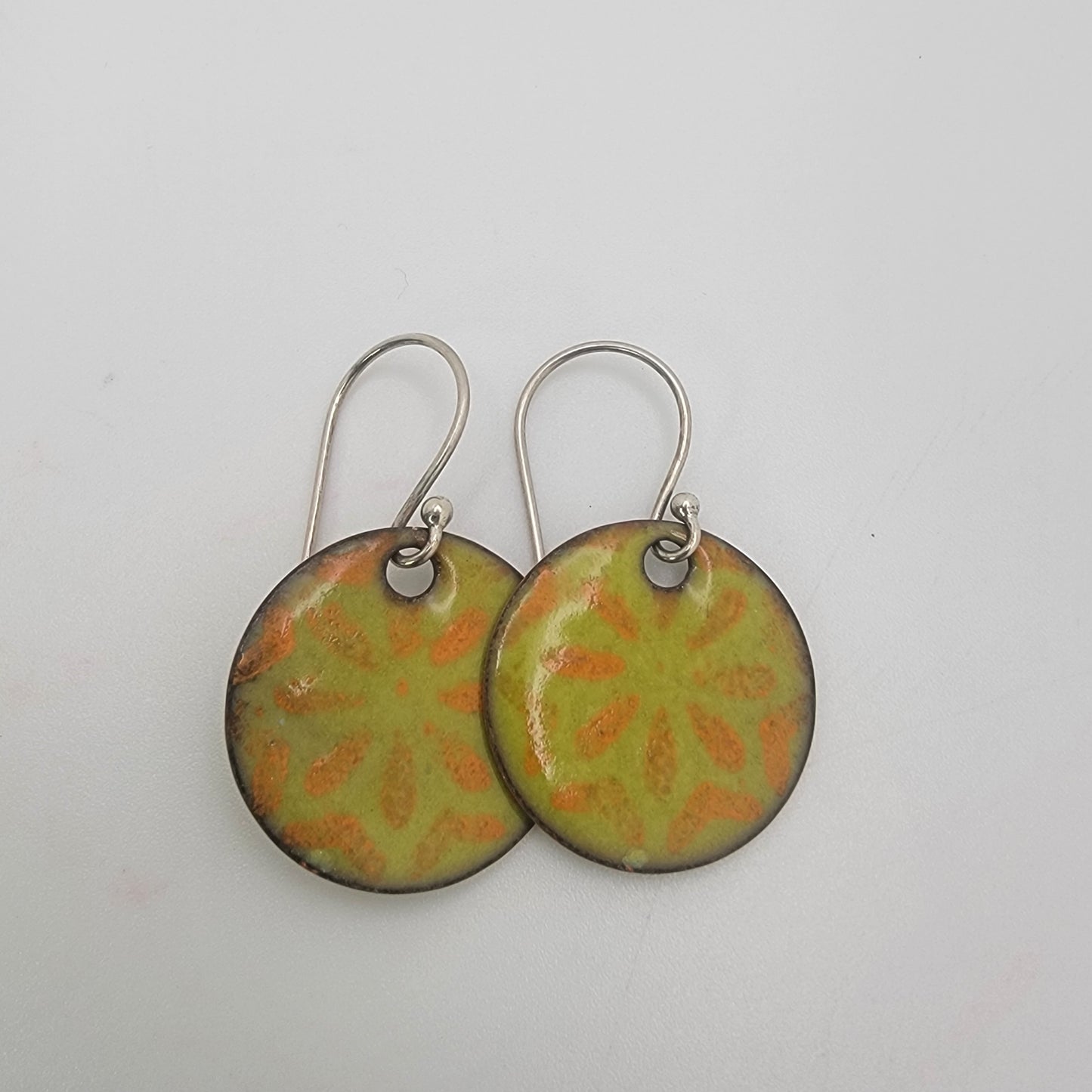 Pair of green and orange patterned earrings on a white background