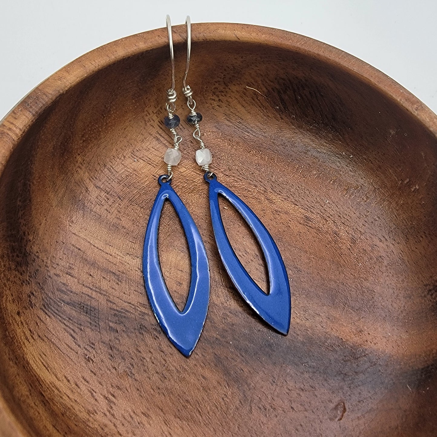 Blue earrings on a wooden bowl