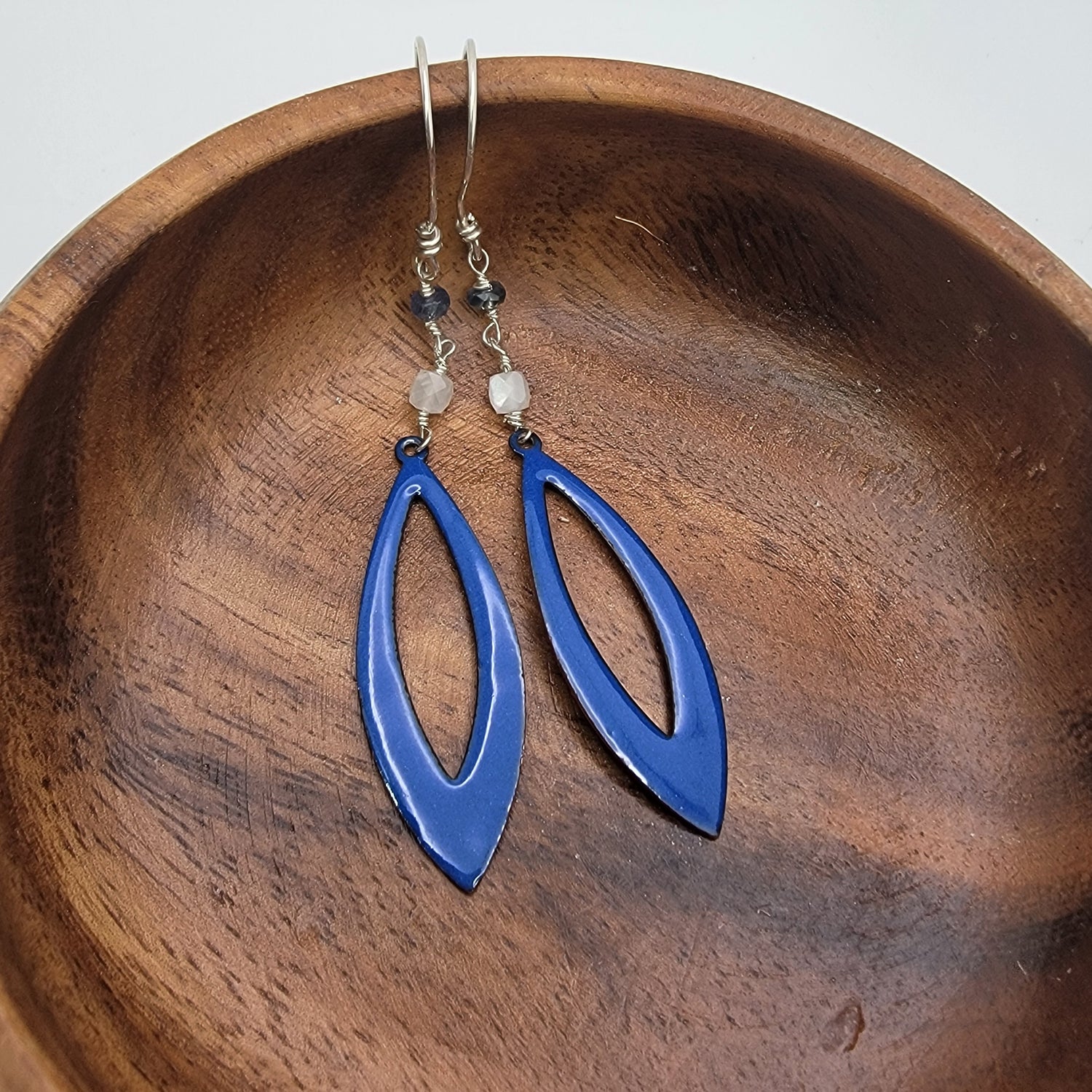 Blue earrings on a wooden bowl