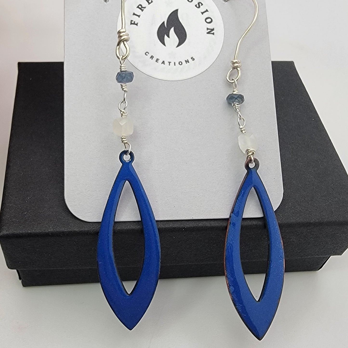 Blue teardrop earrings on a display card with 'Fire and Passion Creations' branding.