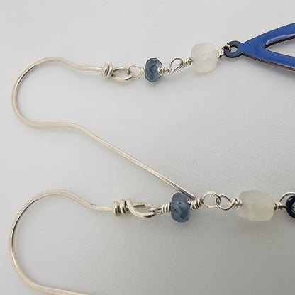 Silver earrings with blue and white beads on a light gray background