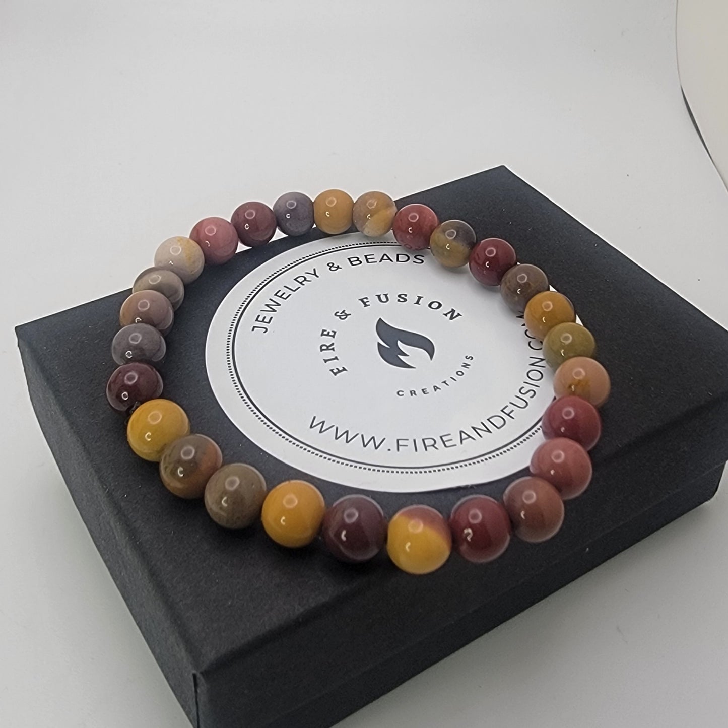 Earth tone beaded bracelet on black branded gift box on a white background