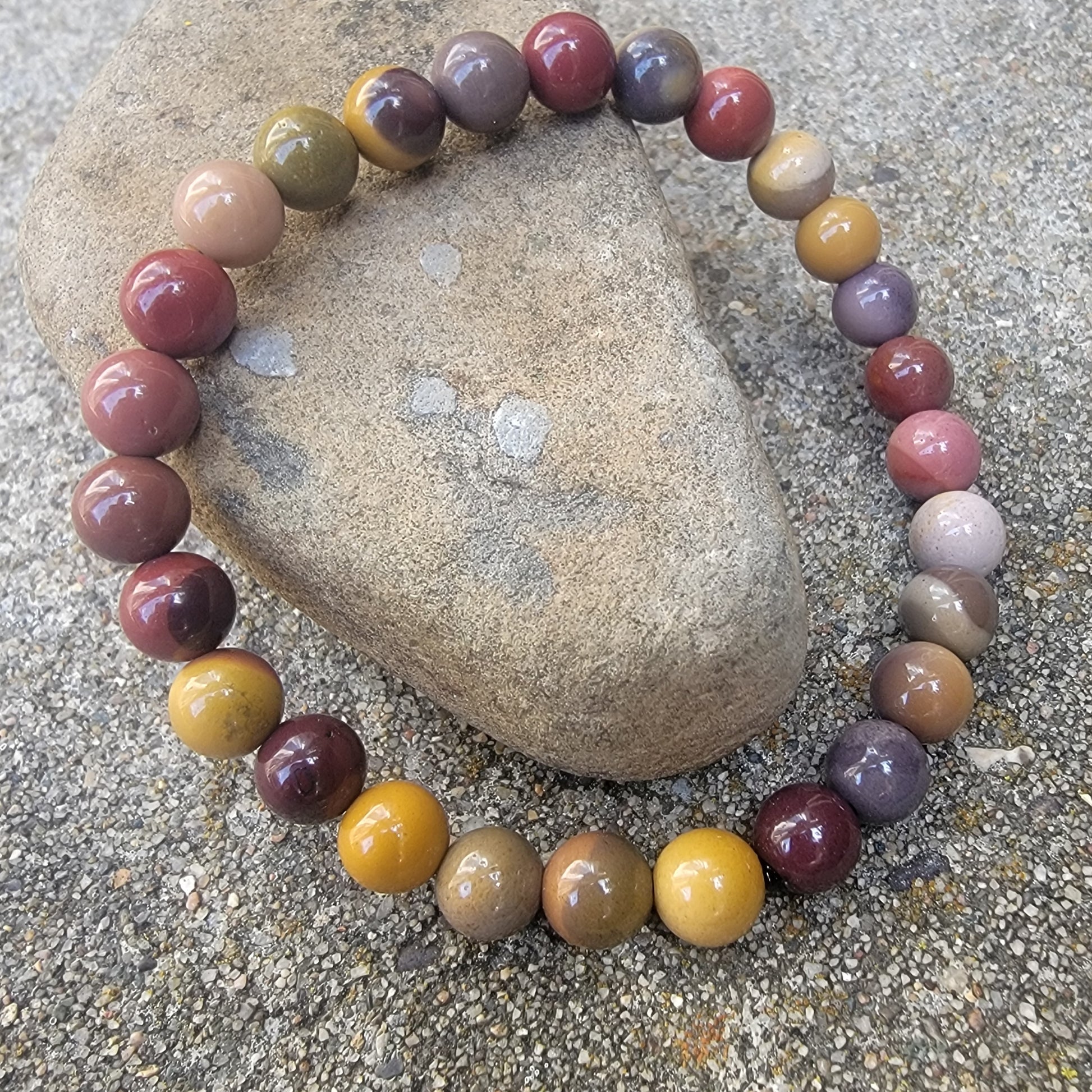 Earth tone beaded bracelet displayed on a rock