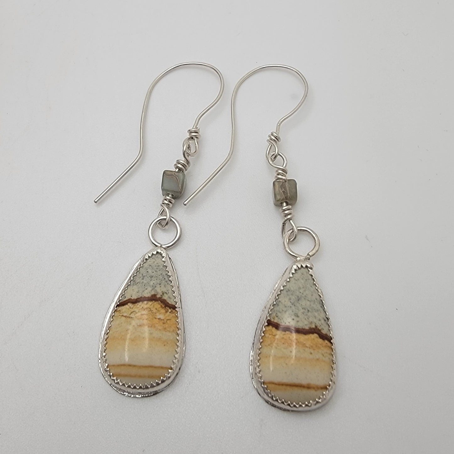 Pair of petrified wood teardrop shaped sterling silver earrings on white background