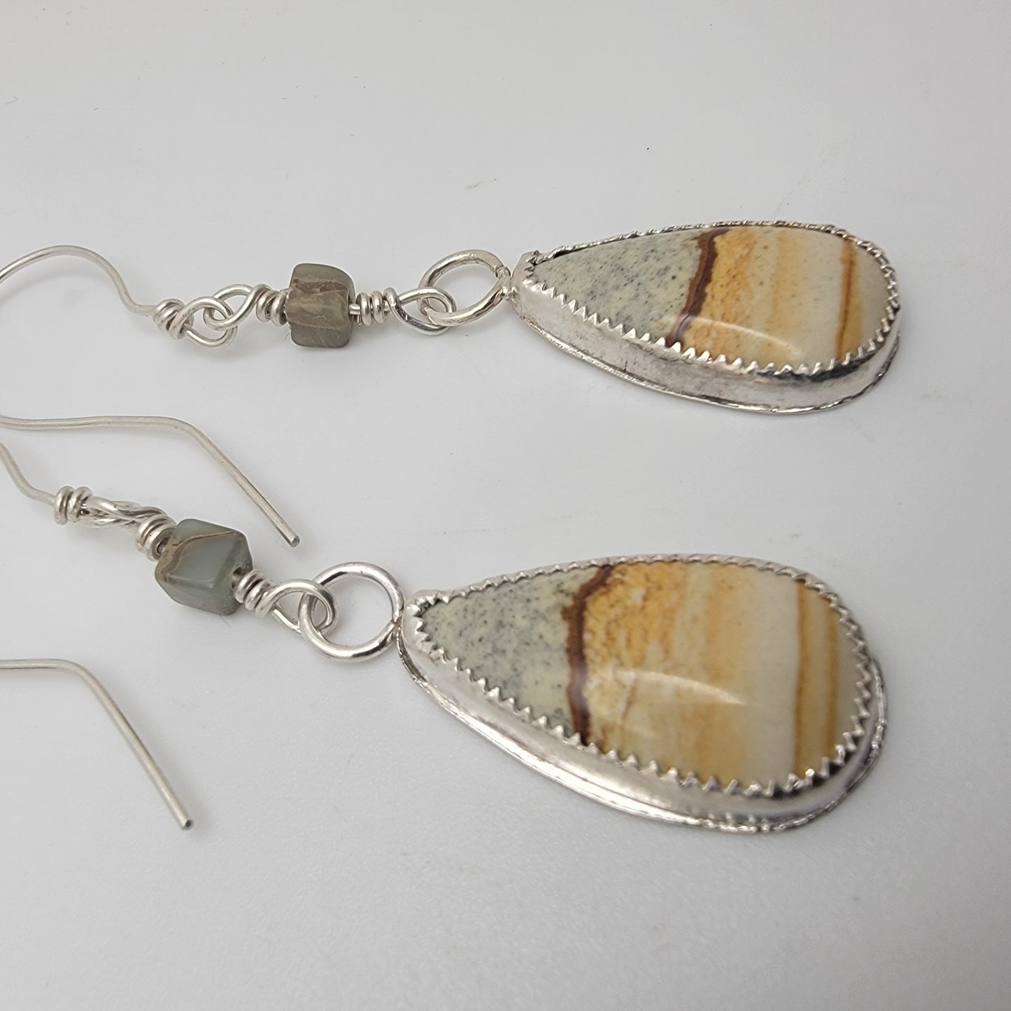 Pair of petrified wood teardrop shaped sterling silver earrings on white background
