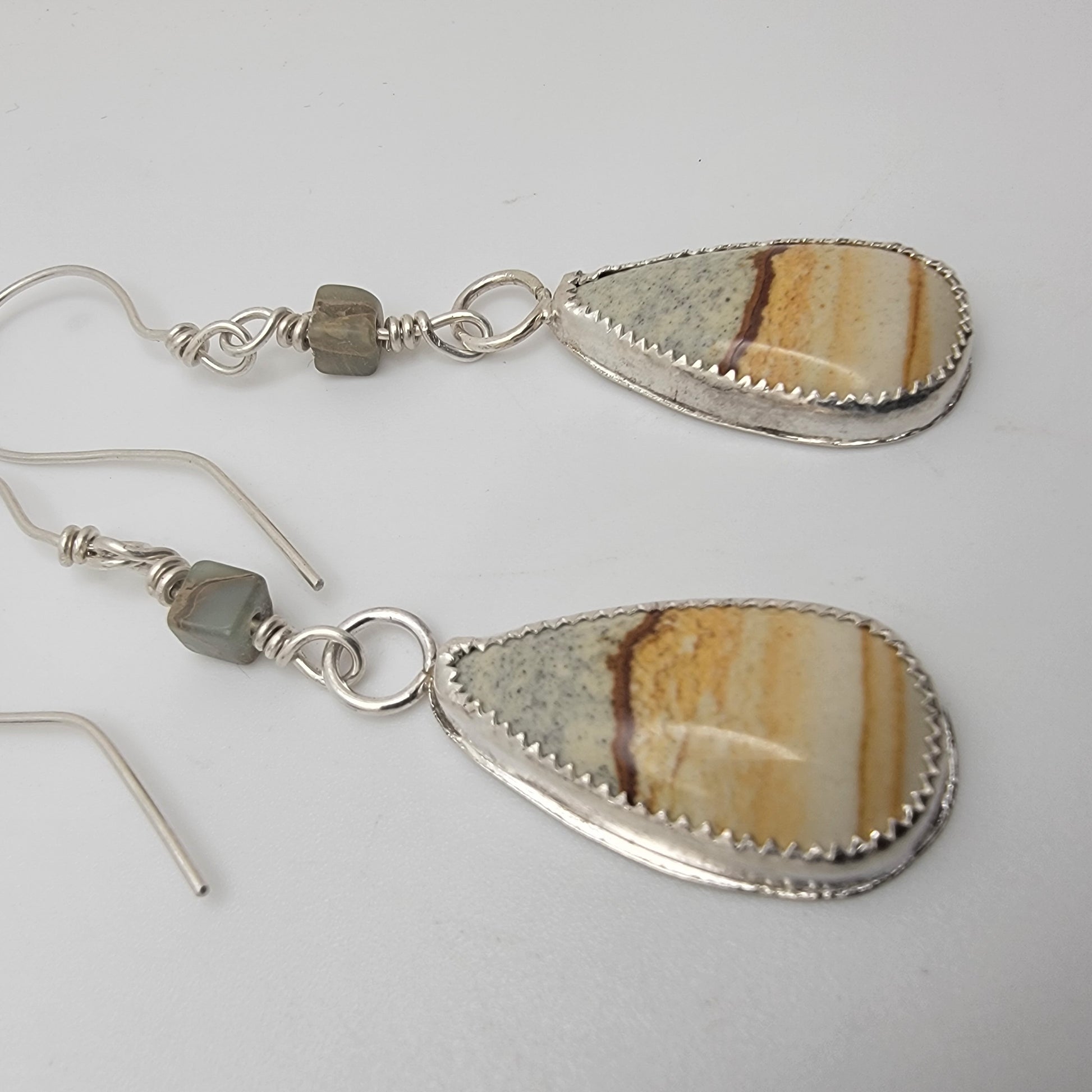 Pair of petrified wood teardrop shaped sterling silver earrings on white background